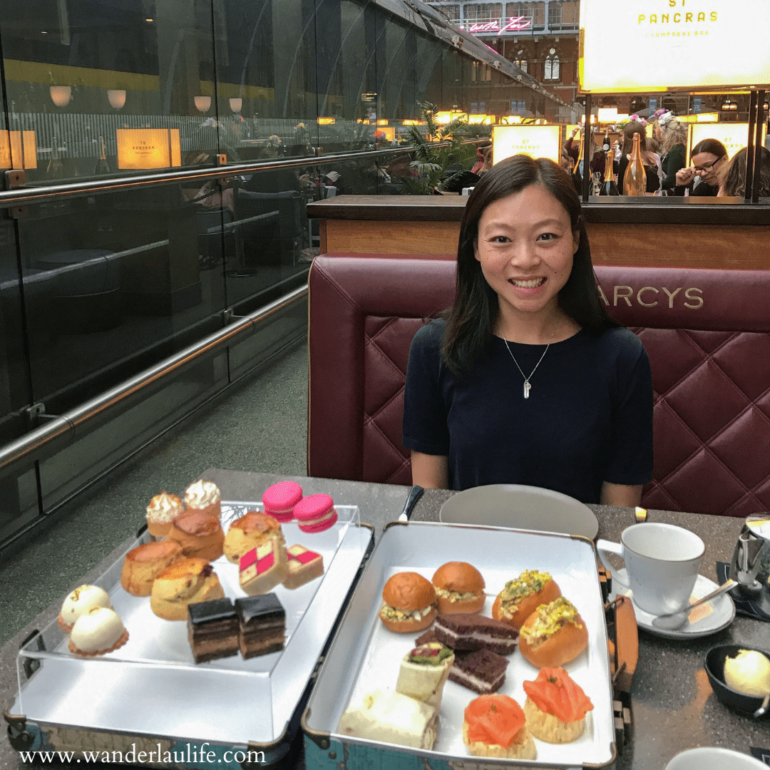 Me enjoying travel-themed high tea in London. The delicious small treats are served in a suitcase and the restaurant is inside St. Pancras Train Station with a view of the trains coming and going.