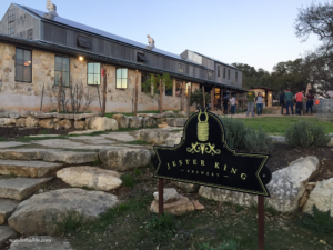 The entrance and ranch building at Jester King Brewery with few people in the background.