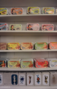 A travel guide to Lisbon includes where to go shopping. A shelf inside A Vida Portuguesa filled with a variety of canned sardines.