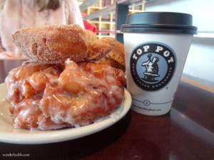 An old-fashioned doughnut and a big cruller on a plate alongside a Top Pot cup of coffee, which is walking distance to a lot of Seattle sites of interest. 