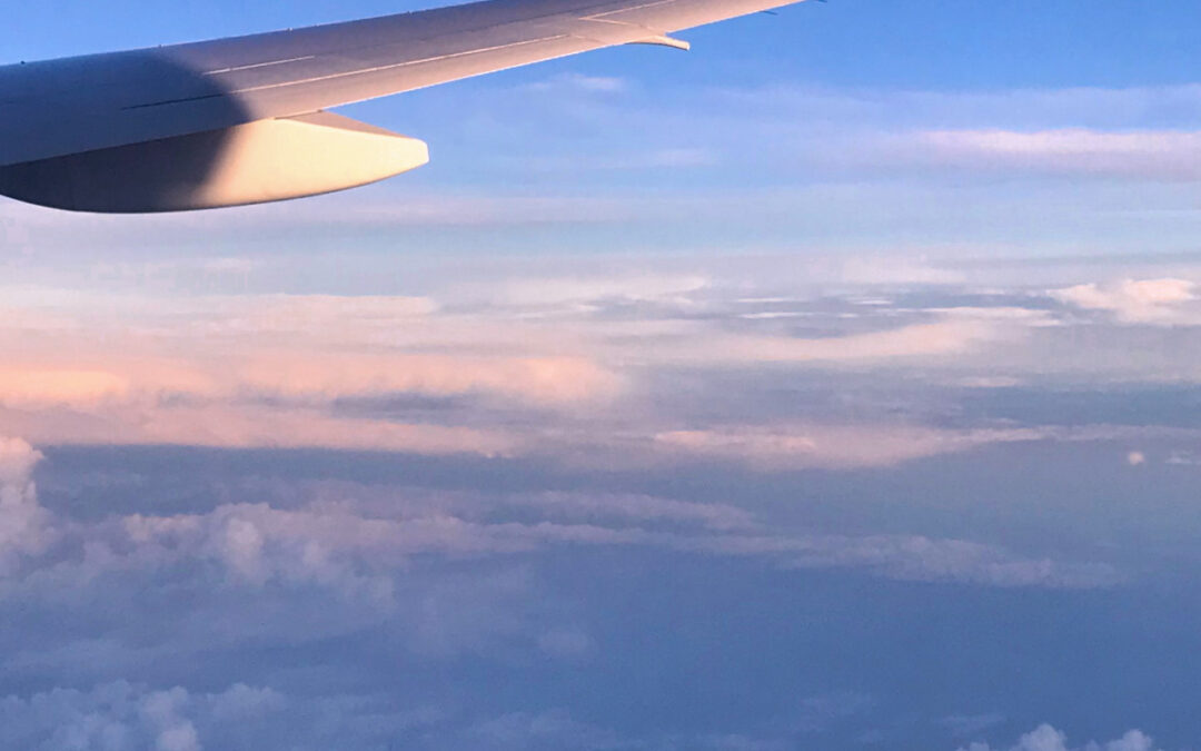 Tips for getting over jet lag: The airplane wing and some fluffy clouds out the window during sunset on one of my flights.