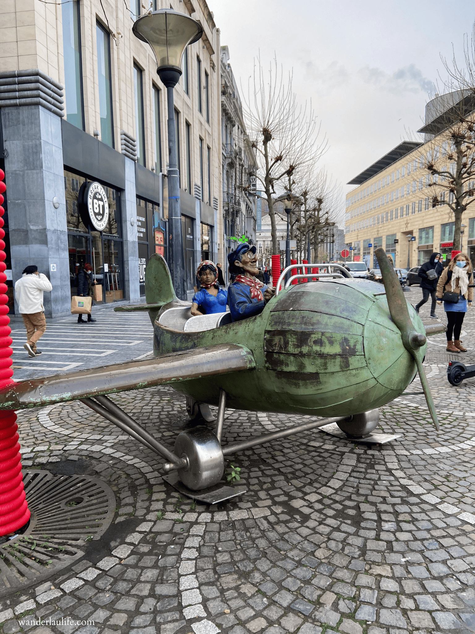 The Tchantchès Pilot Sculpture with few people walking in the background in Liège,