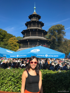 Me standing in front of the Chinese Tower with beer garden umbrellas in the background in Munich.