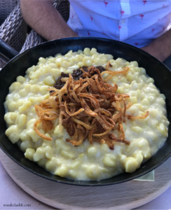 A big bowl of hot Käsespätzle topped with fried onions.