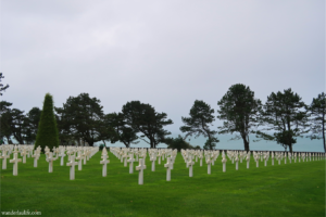 The aligned white gravestones with Omaha Beach behind them at the Normandy American Cemetery.