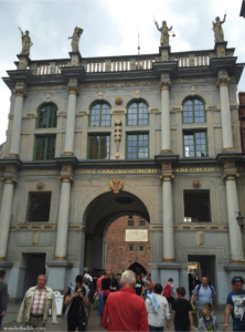 Golden Gate in Gdańsk with several tourists walking around and through it. 